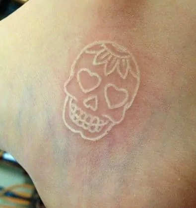 white ink skull tattoo on leg