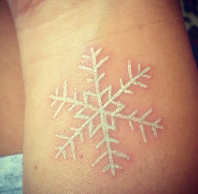 White snowflake tattoo on arm